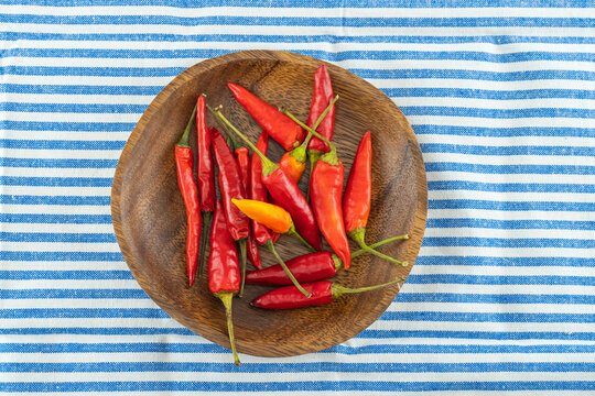 fresh red chili peppers in a wooden bowl on a tablecloth white and blue stripe