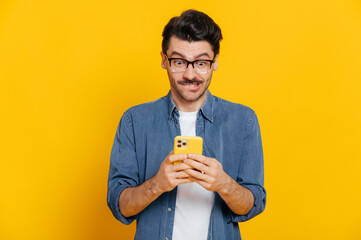 Happy handsome excited stylish guy using smartphone, chatting online, writing message, browsing...