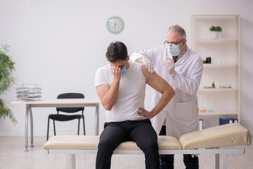 Obraz premium Young male patient visiting old male doctor in vaccination conce