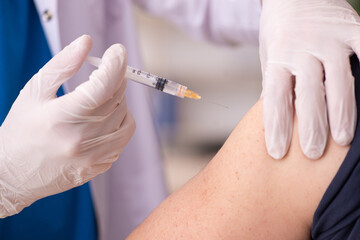 Old man visiting young doctor in covid-19 vaccination concept