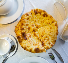 National dish of Georgian cuisine is khachapuri flatbread with cheese, cut into pieces on a plate
