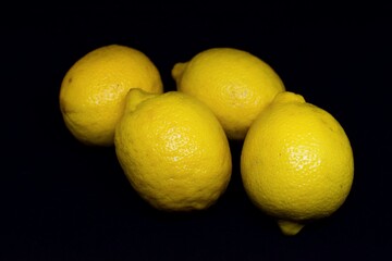 4 lemons with black background.