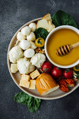 honey stick, cheese board with different types of cheeses: mozzarella, Georgian, cottage cheese, smoked, parmesan, spicy, hard varieties. fresh tomatoes, basil. meat-free snacks, selective focus