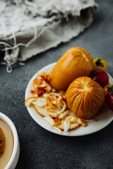 smoked cheese with crust, cheese crumbs and cherry tomatoes on dark table with bowl of honey and wooden stick. types of cheese, options for making products from milk at home, selective focus