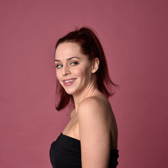 Close up portrait of a red haired woman with expressive facial features on a pink studio background.