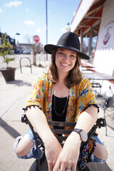Fototapeta na wymiar Woman on sidewalk at cafe in hat