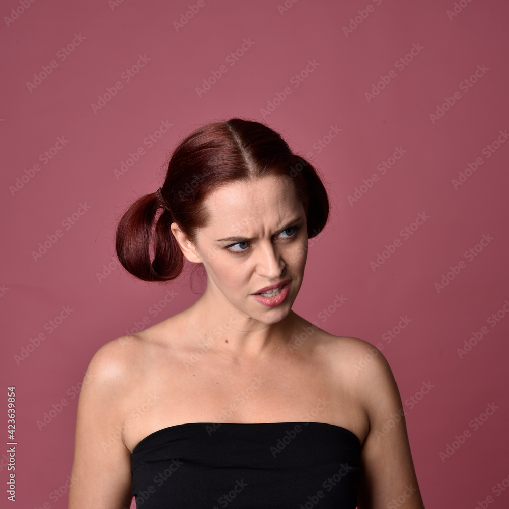 Sticker Close up portrait of a red haired woman with expressive facial features on a pink studio background.