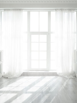 Backlit window with white curtains in empty room