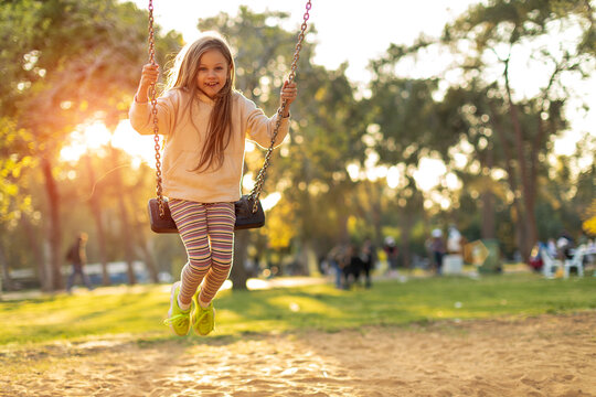 Girl holding chains of swings and swinging