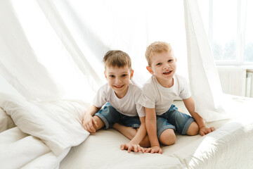 Indoor positive activity. Small children playing on a bed and having fun in sheet hut