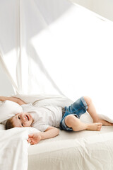 Indoor positive activity. Small sweet child playing on a bed and having fun in sheet hut