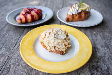 Close up of Almond Croissant and others on wooden table. Croissant is a French buttery, flaky and crescent-shaped bread.