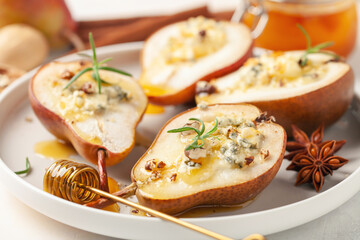 Baked pears with cheese, nuts and honey in a plate on the table.