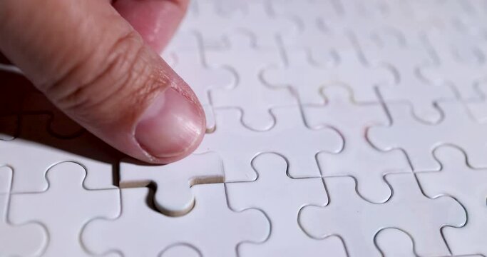 Slow Motion 4K Video close up businessman hand put jigsaw piece to fit together. business concept of solution and business matching. business strategy and marketing plan.
