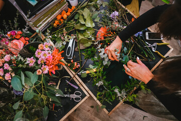 Watching the florist work from above. Assembling a wreath of flowers, leaves and thin branches....
