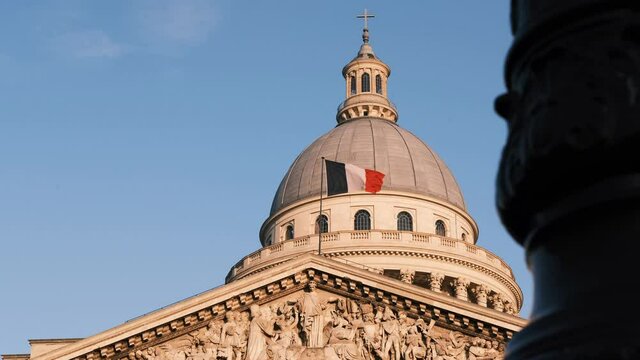 French flag waving in the air on the Pantheon in Paris blue sky sunny day, sliding shot