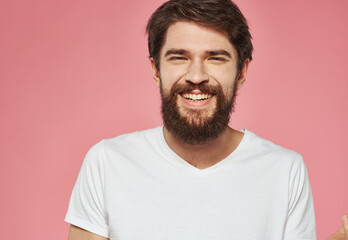 Portrait of a happy man with a beard on a pink background in a white T-shirt
