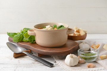 Bowl with tasty garlic soup on light wooden background