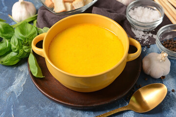 Bowl with tasty garlic cream soup on color background