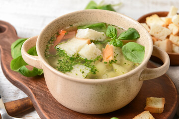 Bowl with tasty garlic soup on wooden background, closeup