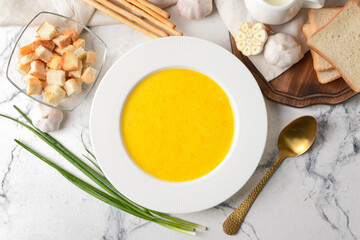 Plate with tasty garlic cream soup on light background