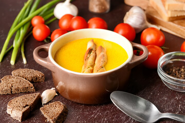 Bowl with tasty garlic cream soup on dark background