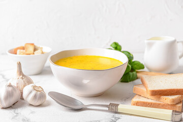 Bowl with tasty garlic cream soup on light background
