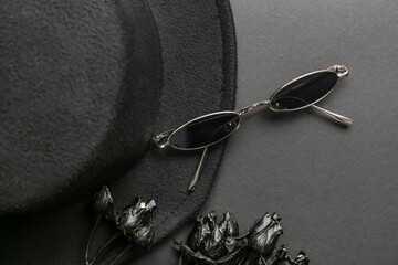 Hat, sunglasses and roses on dark background, closeup