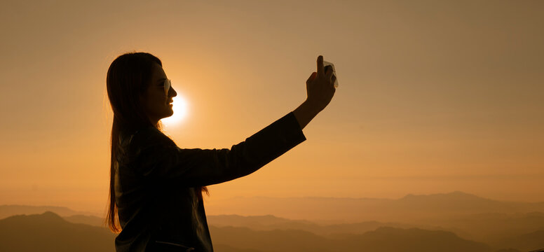Silueta de mujer delgada tom&aacute;ndose selfie con celular en atardecer en las monta&ntilde;as del cerro de la bufa Vallarta Jalisco