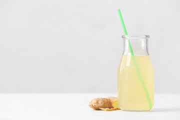Bottle of healthy ginger juice on light background