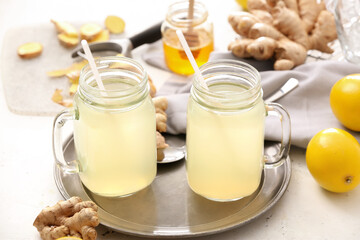 Mason jars of healthy ginger juice on light background