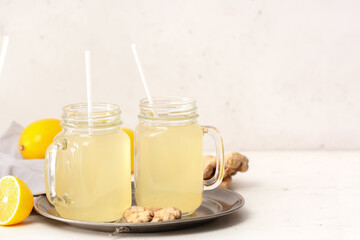 Mason jars of healthy ginger juice on light background