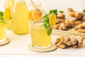 Glass of healthy ginger juice on light wooden background