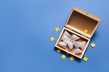 Box with tea bags on color background
