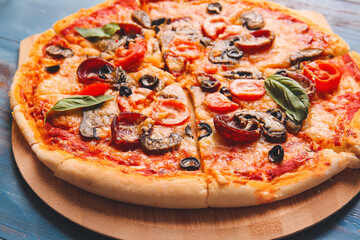 Board with tasty pizza on color wooden background