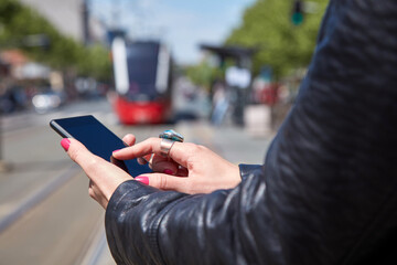 Woman using cellphone on a tram station in Europe.