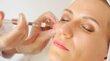 Close-up of a beautician giving an injection into the cheek of a woman.