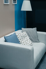 Modern interior design, home comfort and decor, a white sofa with cushions in the living room and a floor lamp against the wall in blue tones