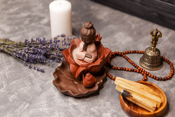 Buddha figure on grey board with an aroma smoke from burning incense sticks flutters on the...