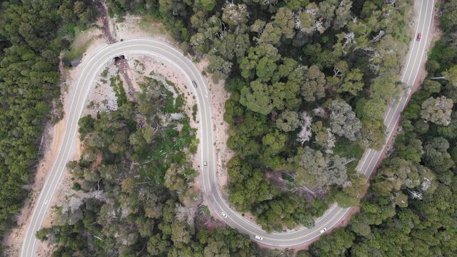 Straight down aerial tracks car traffic on rural highway tight S curve