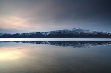 早春の湖面に映る銀嶺の稜線。日本の北海道の屈斜路湖。