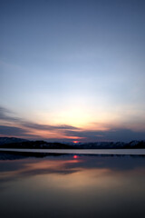 雲の向こうに陽の沈む空を水面に映す黄昏の湖。日本の北海道の屈斜路湖。