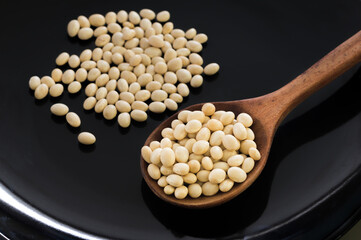 White beans with wooden spoon on black plate.