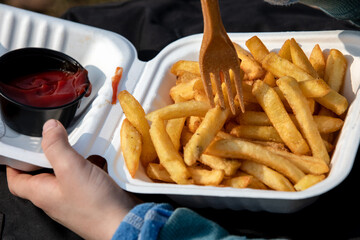 Child eats french fries with ketchup or tomato sauce. Unhealthy food, takeaway and ordering at home