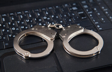 Police metal handcuffs and computer keyboard.