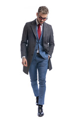 attractive unshaved man looking down and holding hand in pocket