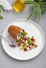 fresh green salad served on a white plate with beans, legumes, and pomegranate seeds