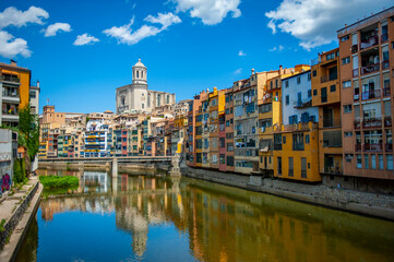 Fototapeta na wymiar Girona, Spain - July 28, 2019: Beautiful colorful riverside houses in the Jewish quarter of Girona city in Catalunya, Spain, with Girona Cathedral in the background