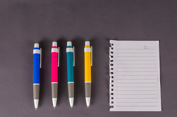 Pens and blank paper on a gray background.