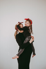 Mother and daughter in same clothes family look having fun together. Pregnant woman with daughter on white background. 